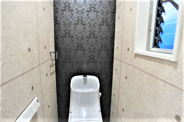 １階トイレ、ベースを廊下と同じ壁紙で一体感を出し正面にはワンポイントで個室を強調